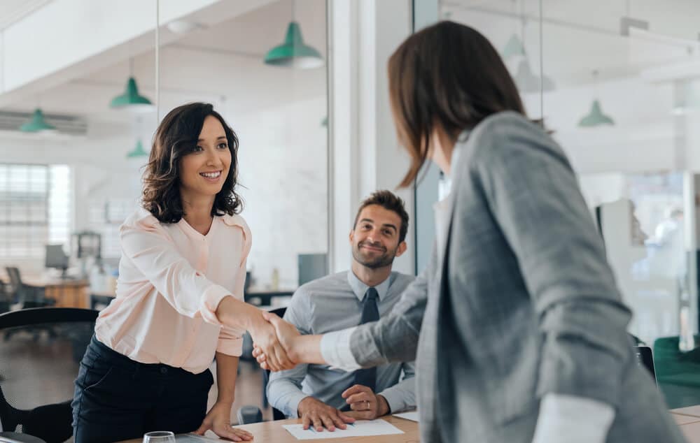 businesswoman shaking hands with an office colleague